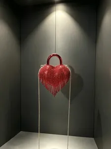 Sac de soirée cœur en strass rouge avec cristaux étincelants, franges et chaîne en métal.