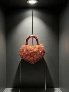 Primo piano di una mini borsa da sera a forma di cuore scintillante di strass rossi.