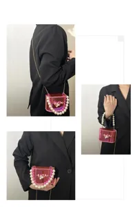 Dettaglio borsa a scatola in acrilico rosa trasparente con manico di perle, borsa donna.
