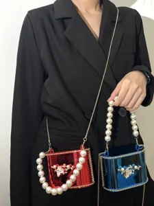 Borsa a mano rigida in acrilico da donna con manico di perle e tracolla elegante.