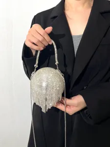 Gros-plan d'un sac de soirée sphérique étincelant en strass avec franges et chaîne en métal.