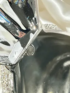 Detailansicht der silbernen Metallic-Abendtasche mit funkelnden Strasssteinen und Magnetverschluss.