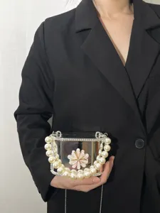 Dettaglio della elegante borsa a scatola in acrilico trasparente con manico di perle.
