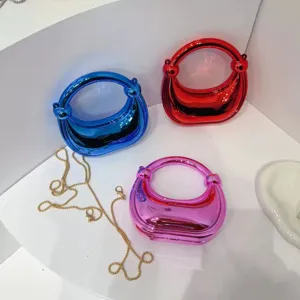 Nahaufnahme trendiger metallischer Minihandtaschen in Blau, Rot und Pink mit Goldketten.