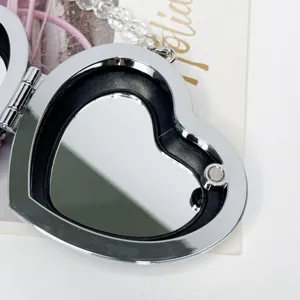 Silberfarbenes herzförmiges Metall-Etui mit Spiegel und Verschluss für stilvolle Damenaccessoires.