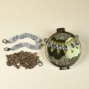 Nahaufnahme Detail der runden Metalltasche mit Kristallriemen und goldenen Ketten.