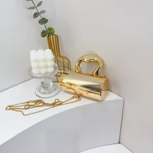 Goldene metallische zylindrische Abendtasche Detail, mit Griff und schicker Kette.