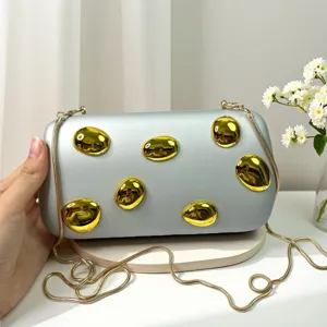 Detailansicht der Acryl-Clutch Tasche mit glänzenden goldenen Schmucksteinen und Metallkette.