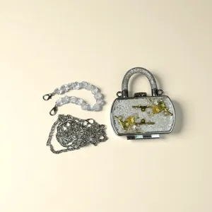 Nahaufnahme einer Mini-Clutch mit Strassgriff, Blumendekor und zwei verschiedenen Ketten.