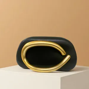 Black mini handbag with gold sculptural metal handle for evening party and daily trendy look.