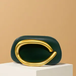 Exquisite detail of dark green leather evening bag featuring a striking bold gold metal ring handle.