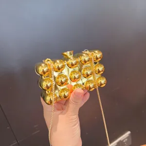Vista dettagliata di una borsa pochette a sfera metallica dorata con catena per eventi.