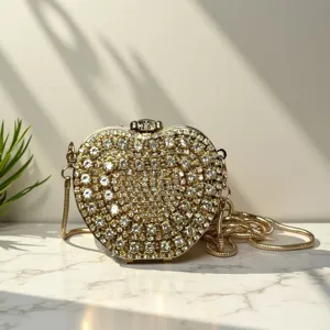 Detailansicht der glitzernden Kristall Apfel Clutch Tasche mit goldener Kette auf Marmor.