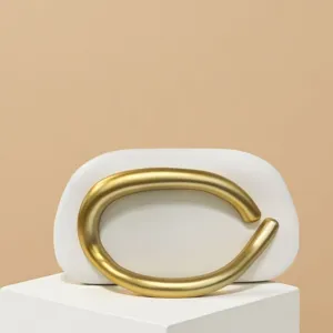 Detail shot of mini white shoulder bag featuring a striking vintage gold circular metal handle.