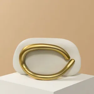 Elegant minimalist shoulder bag featuring a bold gold metal ring handle for evening style.
