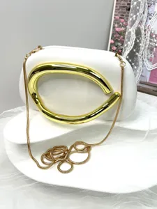 Detailed view of white evening clutch bag with luxury gold metal handle and chain.