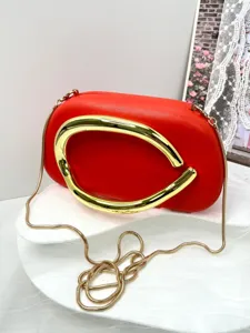 Elegant red leather clutch bag featuring a statement gold metal handle and chain strap detail.