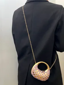 Detailansicht einer glamourösen Abendtasche mit rosa Strasssteinen und filigraner goldener Kette.