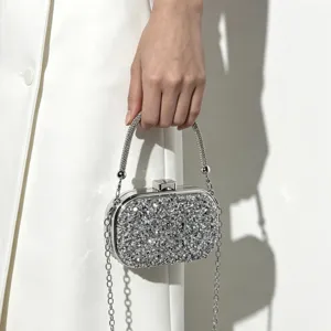 Close-up detail of a sparkling silver evening clutch bag with chain strap and rhinestone handle.