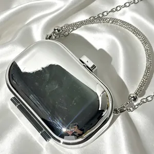 Silver metallic evening clutch bag with sparkling rhinestone handle for party and wedding events.