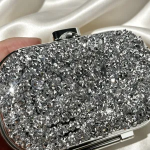 Sparkling silver rhinestone evening clutch bag detailed close-up showing crystal texture.