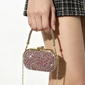 Sparkling pink rhinestone clutch bag detail view, golden metal frame and delicate chain strap.
