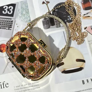 Rhinestone mini evening clutch bag detail, luxury gold acrylic shell with sparkling crystal chain.