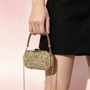 Detailed close-up of sparkling rhinestone evening clutch bag with gold chain, elegant fashion item.