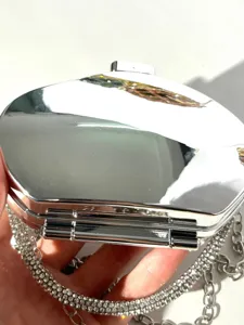 Silver mirror finish evening clutch bag detail showing sparkling rhinestone chain strap.