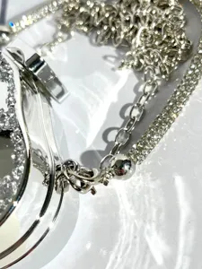 Rhinestone acrylic evening bag detail close up, shiny diamond shoulder cross body purse hardware.