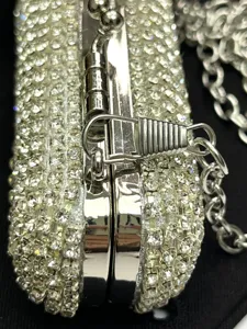 Close-up of rhinestone evening box bag clasp and chain detail, sparkling crystals.