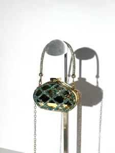 Close-up detail view of glamorous diamond evening bag with green crystal lattice and gold chain.