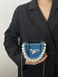 Dettaglio borsa box in acrilico blu trasparente con bordo di perle e catena elegante.
