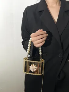 Dettaglio borsa rigida sera perle acrilico oro effetto specchio con elegante fiore decoro.