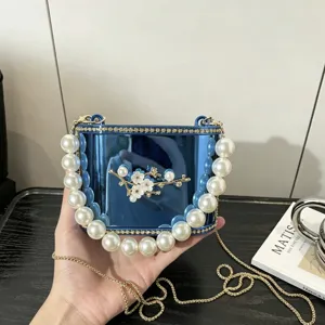 Borsa a mano rigida in acrilico blu con grande manico di perle e spilla floreale chic.