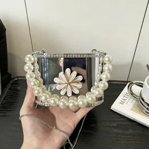 Dettaglio borsa box in acrilico con finitura argento, bordo di perle e decoro floreale.