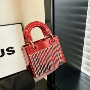 Red glossy acrylic evening bag detail featuring sparkling rhinestone fringe and metal handles.
