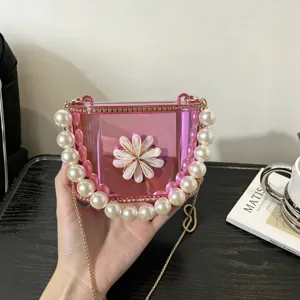 Borsa a scatola in acrilico trasparente rosa con elegante manico di perle e tracolla a catena dorata.
