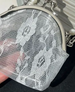 Detailed view of a vintage white lace clasp coin purse with elegant silver metal frame.