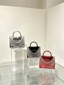 Detailansicht von Acryl Abendtaschen mit funkelnden Strassfransen und elegantem Henkel.