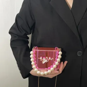 Borsa a mano in acrilico rosa chic con manico di perle e moderna tracolla a catena.