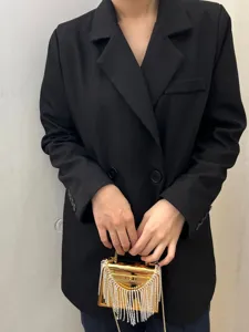 Detailansicht der goldenen Acryl-Box-Abendtasche mit funkelnden Strassfransen und Griff.