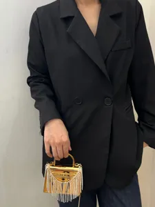 Detailansicht der luxuriösen goldenen Acryl Abendtasche mit funkelnden Strass Quasten und Griff.