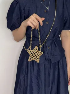 Detail en gros plan du sac bandouliere etoile metallique ajouree avec chaine dosee.