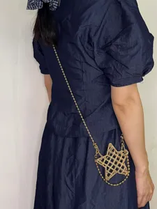 Gros plan d'un mini sac bandoulière métallique ajouré en forme d'étoile avec chaîne perlée.