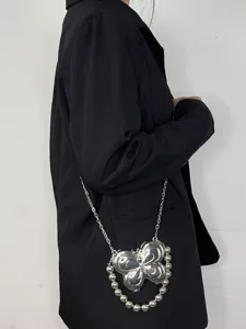 Nahaufnahme des kreativen silbernen Schmetterlings-Metall-Umhängetaschendetails mit Perlen.