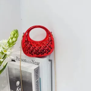 Detailed shot of shiny red hard-shell crossbody bag with circular handle and chain.