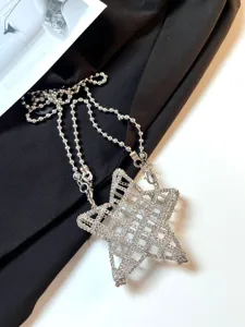 Détail de mini sac bandoulière creux en pentagramme métallique argenté avec design d'étoile.