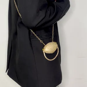 Detaillierte Nahaufnahme einer luxuriösen goldenen Strass Mini Umhängetasche mit Metallkette.