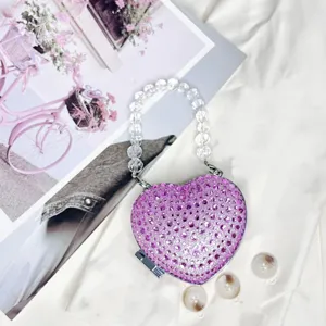 Herzförmige Strass Mini Clutch Tasche Detail, glitzernde lila Kristalle mit Perlenhenkel.